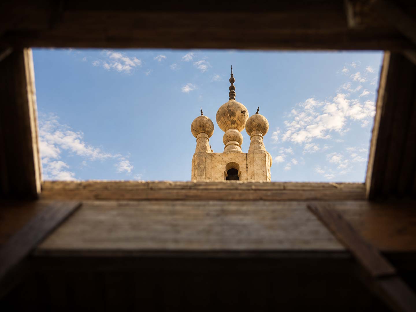 إطلالة علوية مميزة من خلال كادر خشبي تُظهر القباب الثلاث الفريدة لمئذنة مسجد ومدرسة السلطان الغوري في شارع المعز — صورة 12