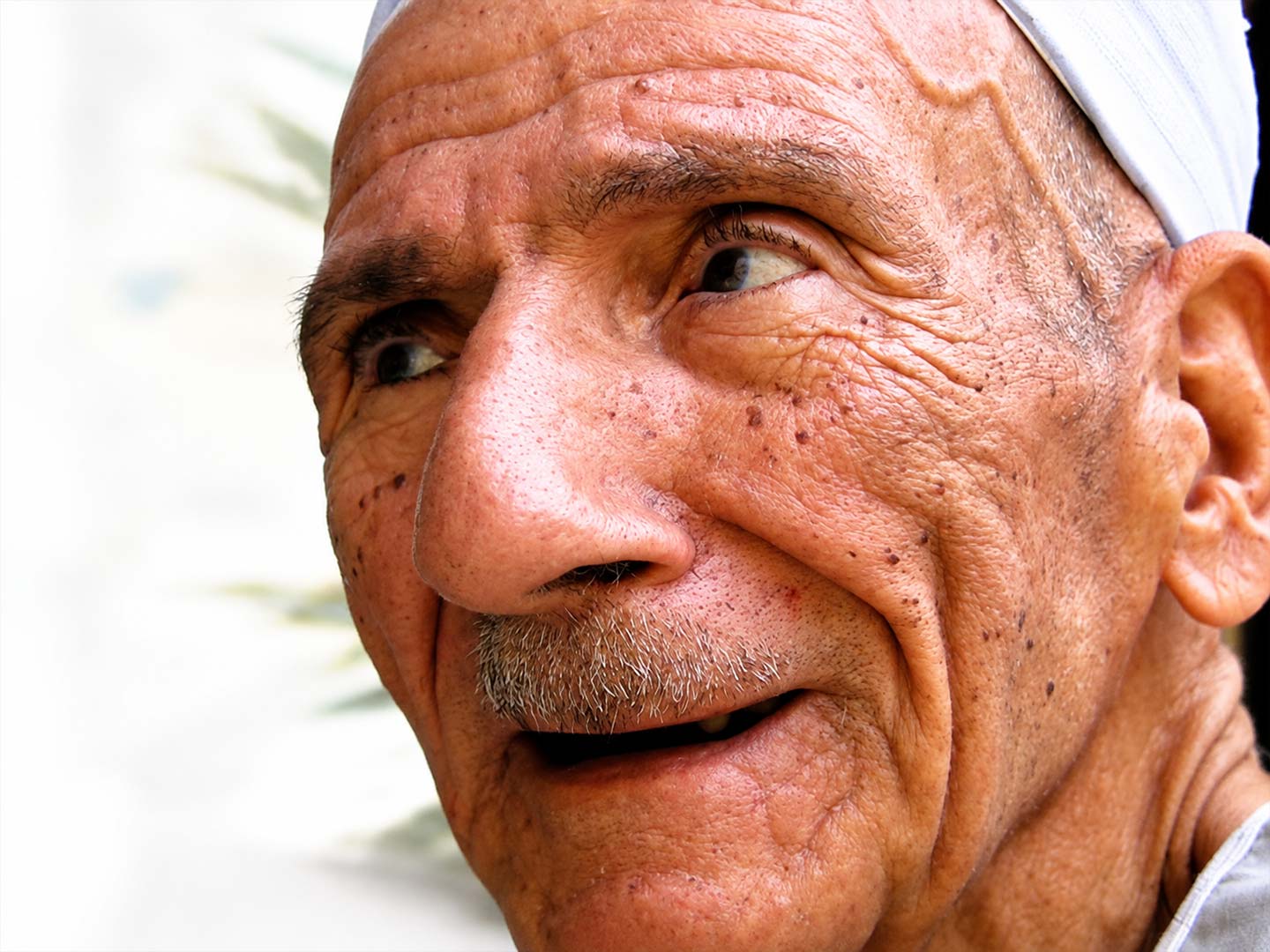 لقطة قريبة (كلوز أب) تبرز تفاصيل ملامح وتجاعيد وجه رجل مصري مسن بابتسامة أصيلة في شارع المعز — صورة 3